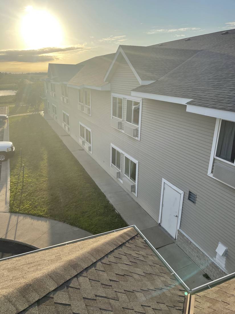 Rooftop view down the wing of the GrandStay Hotel & Suites in Waseca, MN, with its shingle roof, lap siding and first-floor entries