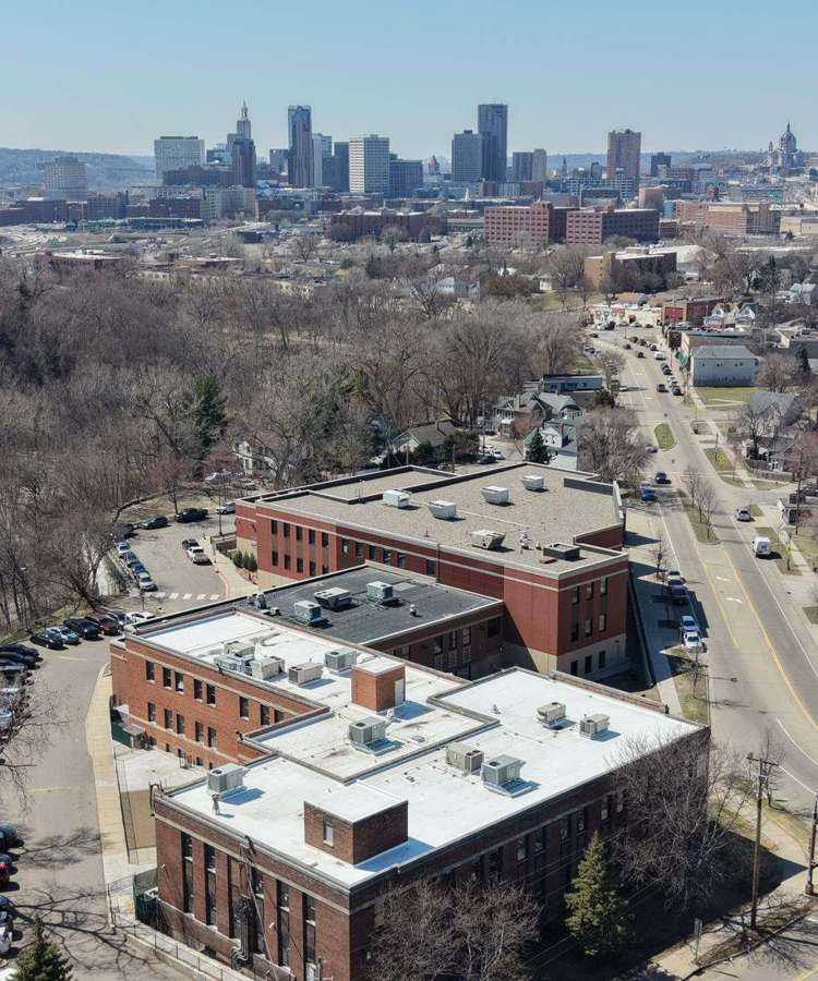 Aerial view over a commercial roof near Payne Avenue with the downtown St. Paul skyline in the background, April 2026