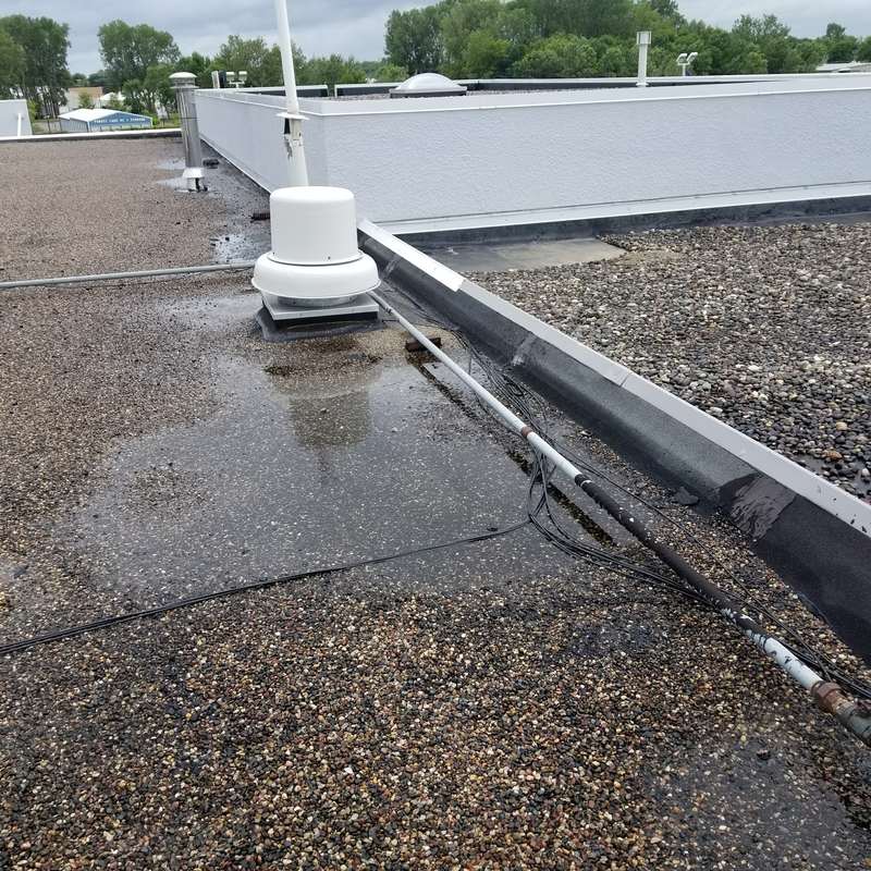 Standing water and vents on the old gravel roof at the Forest Lake dealership before the job