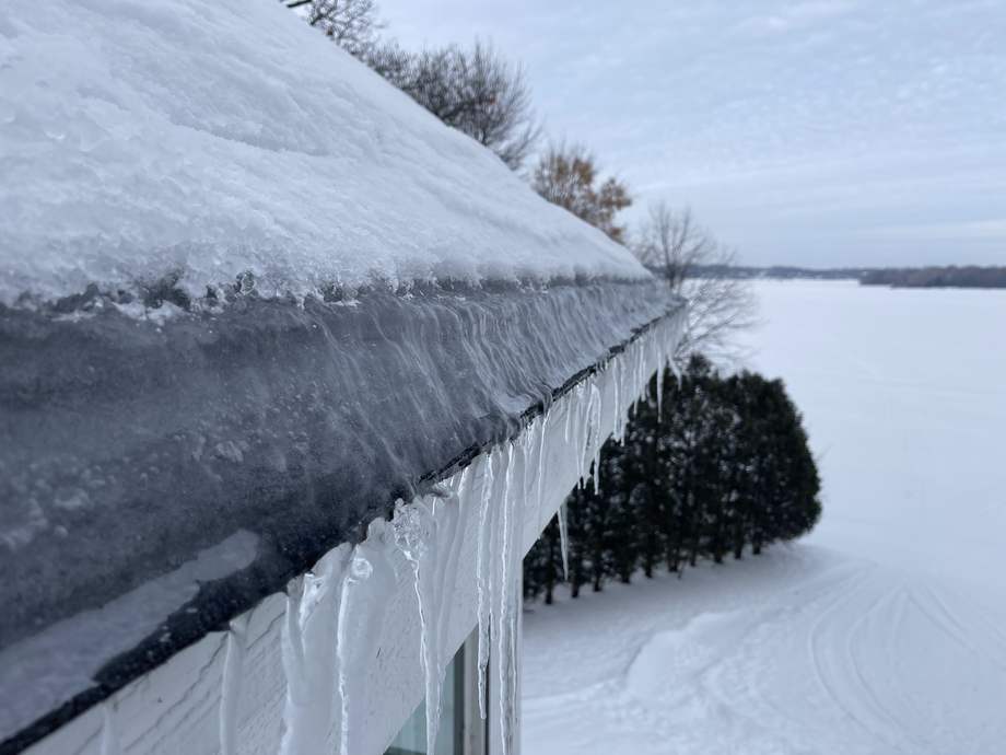Thick ridge of ice built up over a gutter with icicles below