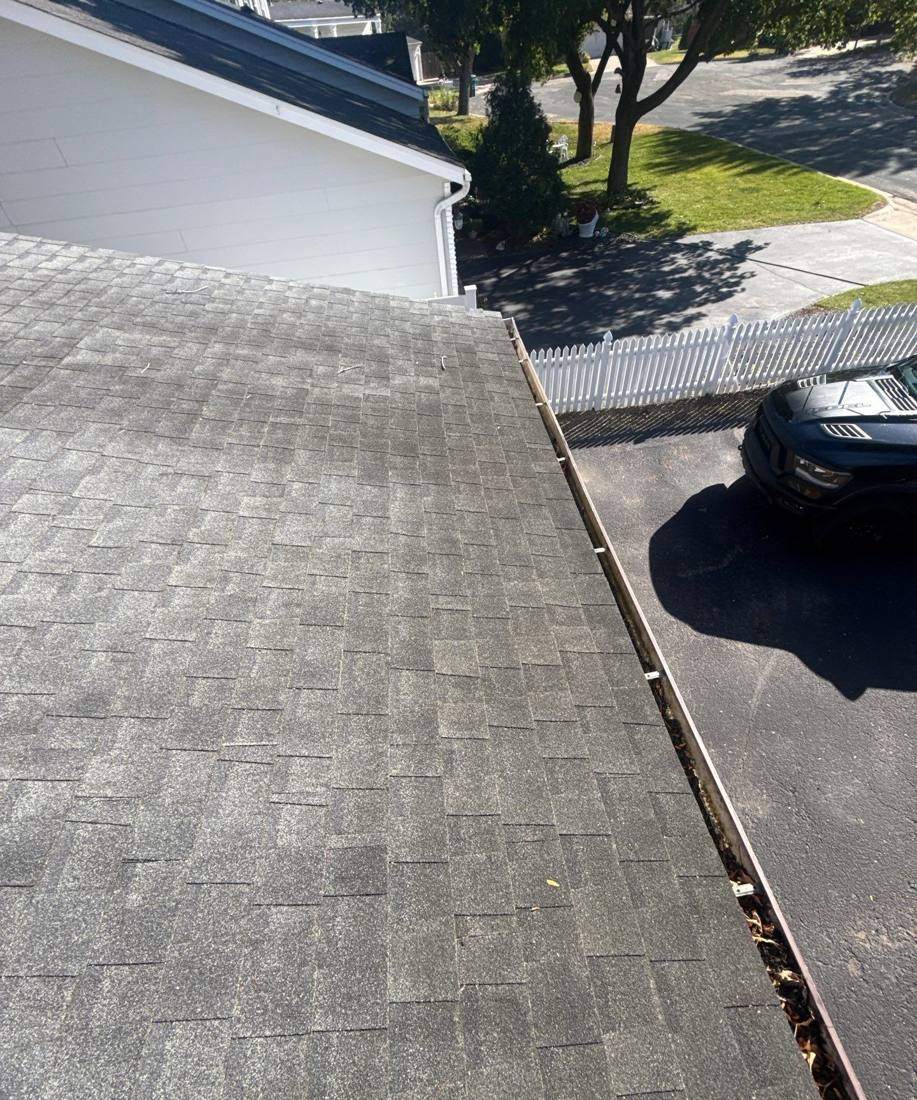 View down a Burnsville roof edge and gutter line toward the street, October 2025
