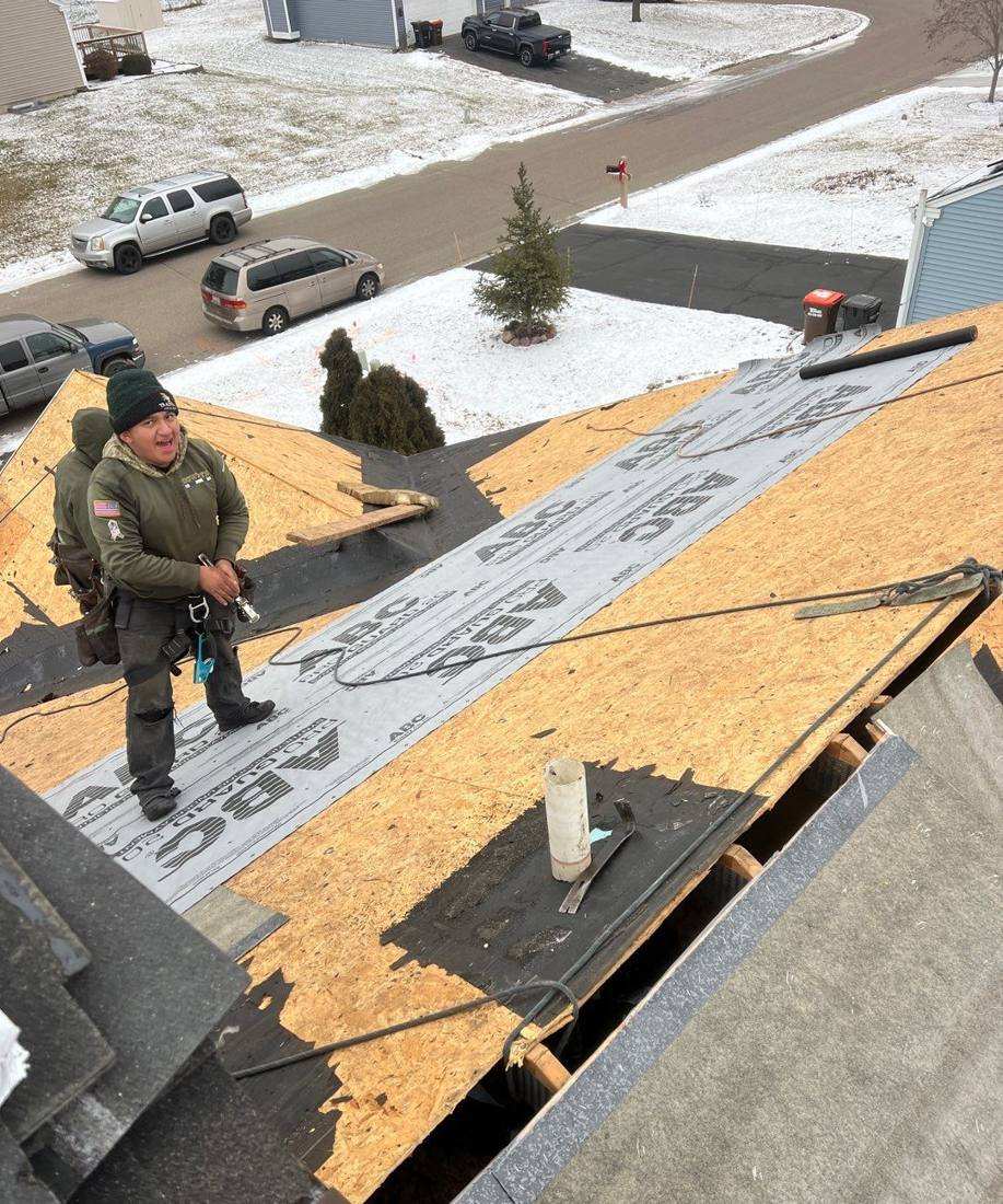 Crew member on the decking during a Maplewood tear-off, new synthetic underlayment down, January 2024