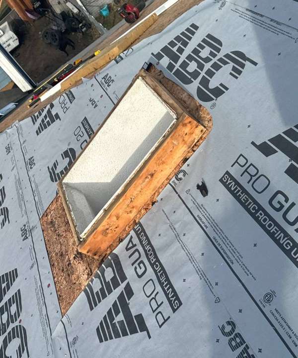 Skylight opening framed on new synthetic underlayment during a Burnsville tear-off, December 2023