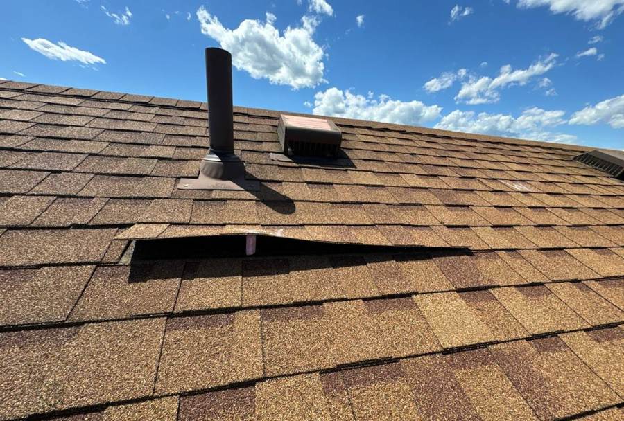 Creased, lifted shingle tab below the roof vents on a Pine County motel roof in Finlayson, June 2024