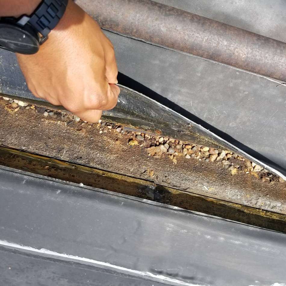 Hand lifting the membrane at a rooftop gas line on King of Glory Lutheran Church in Blaine, July 2017