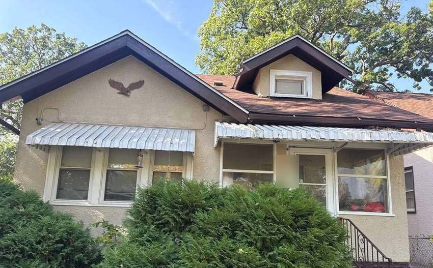 North Minneapolis bungalow with a folk-art eagle over the porch, photographed during a roof project, October 2025