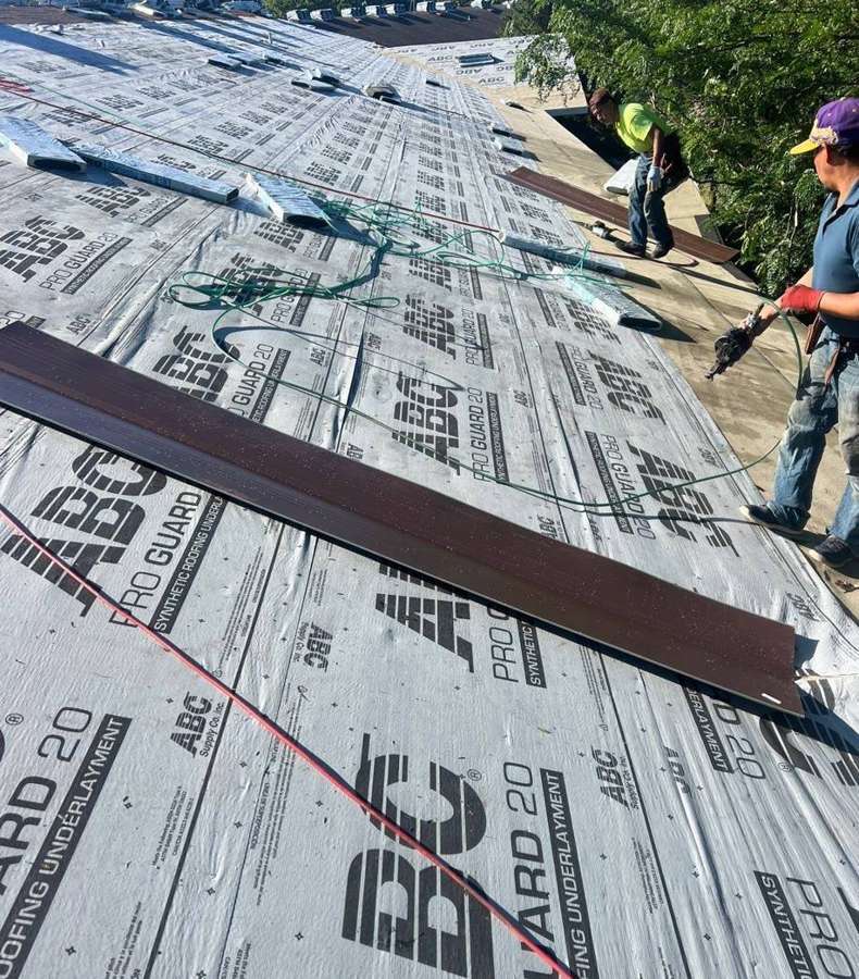 Repair King roofer laying synthetic underlayment on an apartment roof in Hutchinson, August 2024