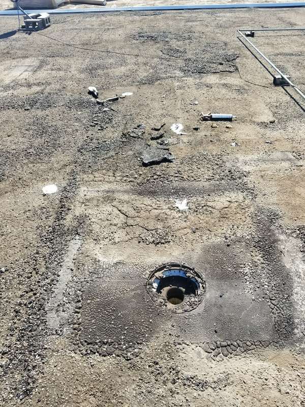 The stripped old roof surface around a drain, ready for new insulation, at the Forest Lake dealership