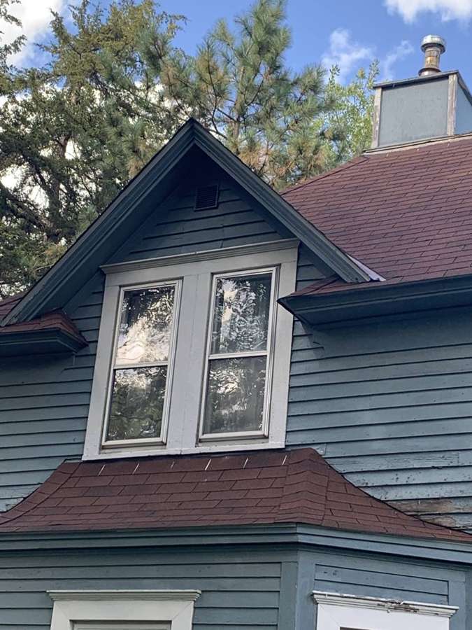 Gabled dormer and chimney on an older clapboard home in Watertown, MN