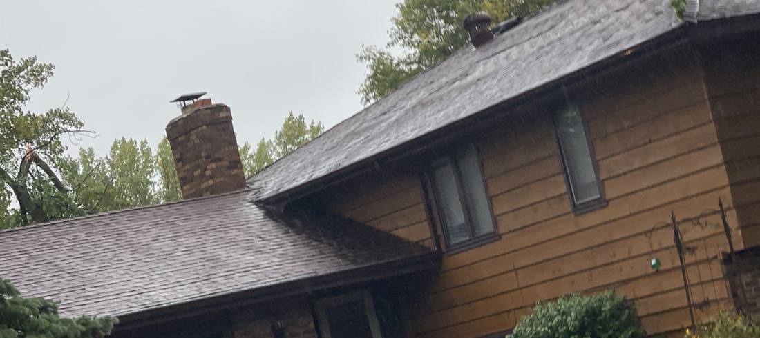 Storm-damaged tree limb over an Apple Valley roofline during an inspection, September 2021