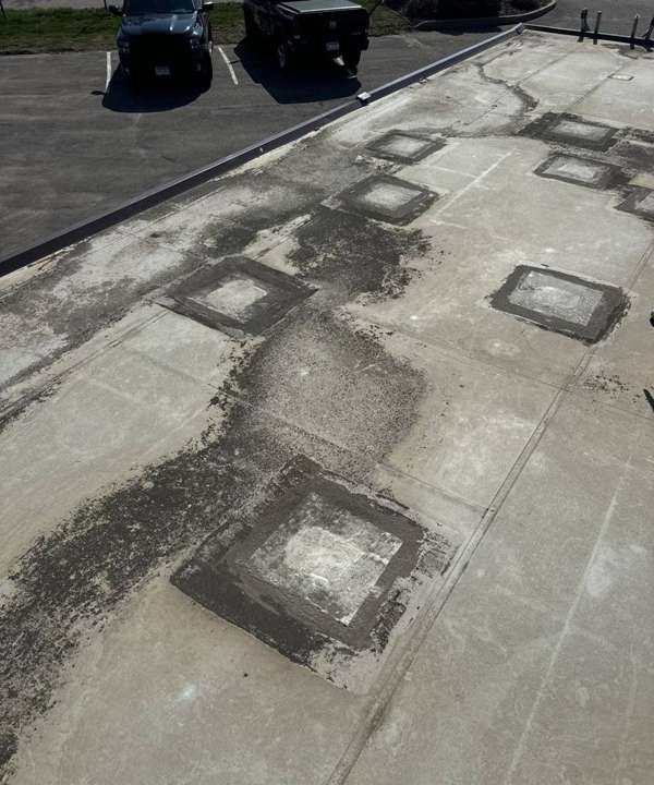 Square membrane patches with dark staining on the low-slope roof of an iStorage facility in Burnsville, April 2024