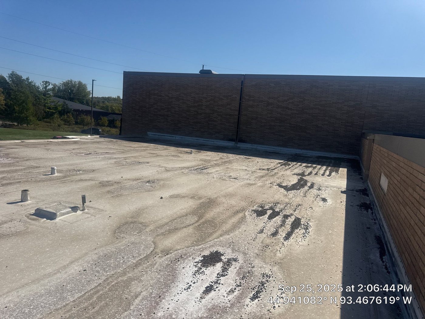 Wide view of the low-slope roof field and brick wall at Minnetonka Christian Academy during Repair King's September 2025 post-storm inspection