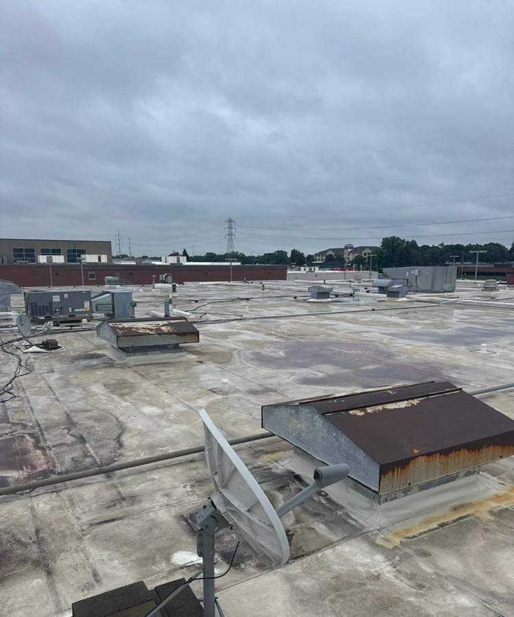 Old flat roof with a roof hatch, satellite dish and rooftop units on the Bloomington Lincoln dealership in Bloomington, MN, July 2024
