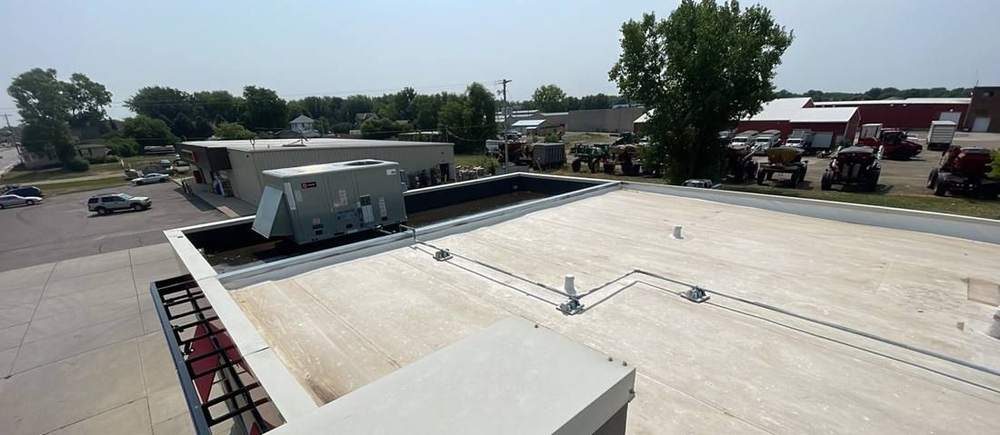 View across the low-slope roof of the Cokato Dairy Queen toward the Highway 12 business strip, photographed by Repair King in July 2023