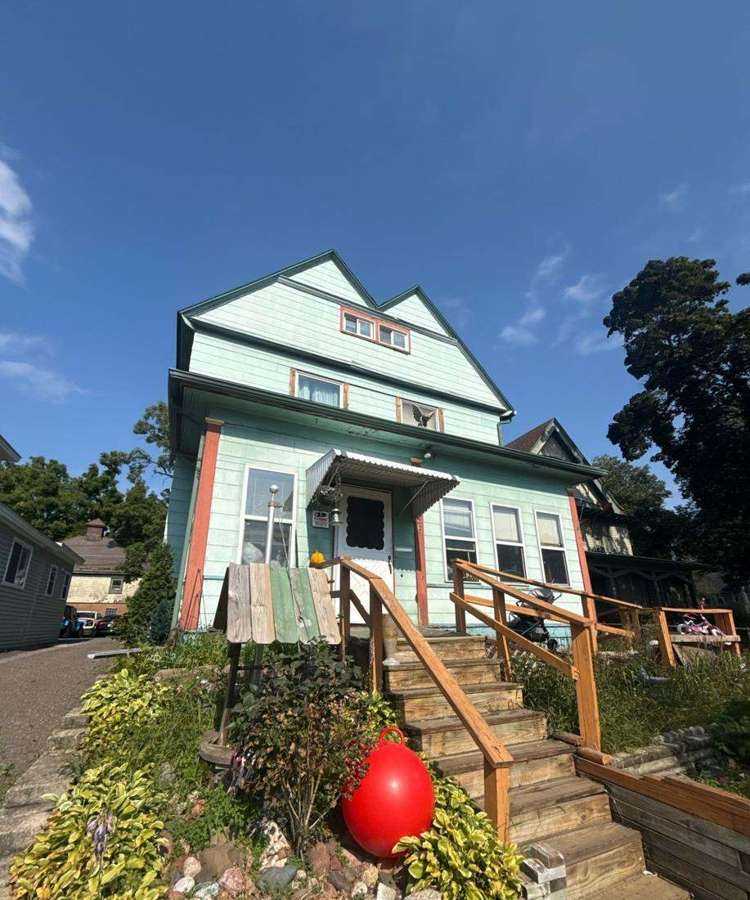 Green Queen Anne-style home on the East Side, photographed during a St. Paul roof project, August 2025