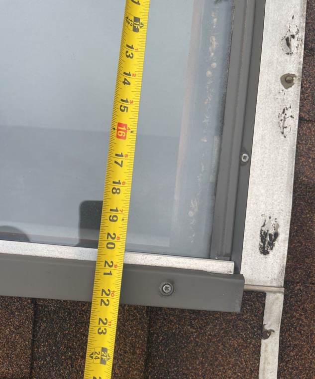 Tape measure along a dented skylight frame on a Wyoming roof, October 2021