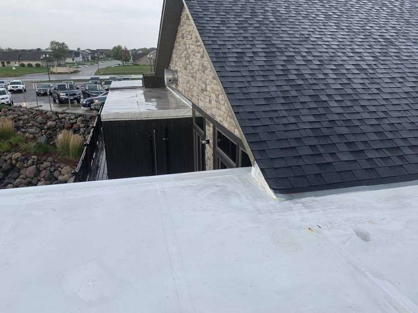 Flat white Duro-Last roof section meeting the shingled clubhouse roof at Coyote Moon Grille, Territory Golf Club, St. Cloud, MN