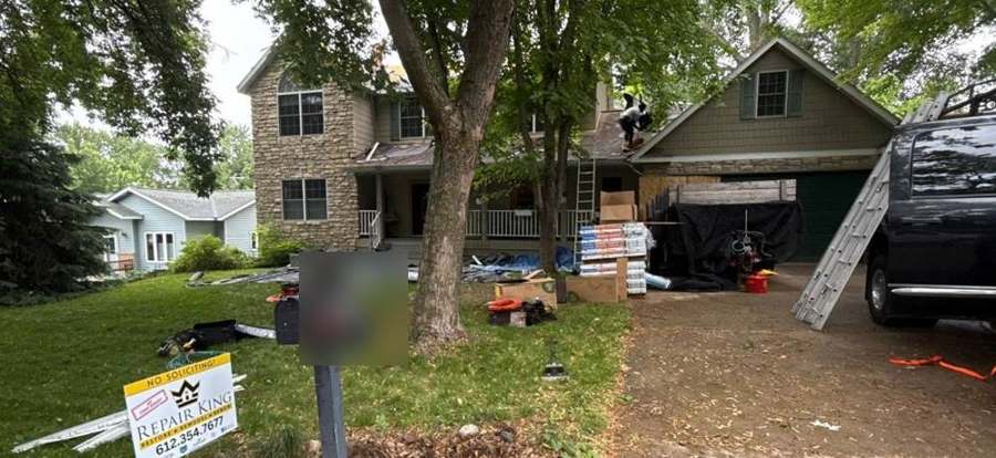 Repair King yard sign, shingle bundles and a crew on the roof of a two-story home on Suzanne Avenue in Shoreview, MN, June 2026