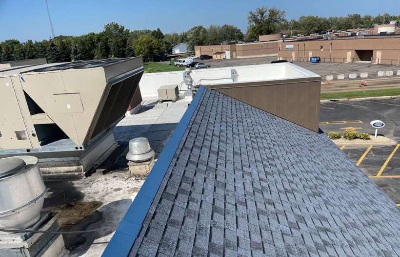 Rooftop HVAC units and exhaust fans on the flat roof behind the shingled hip roof of Culver's in Waite Park, MN, September 2021