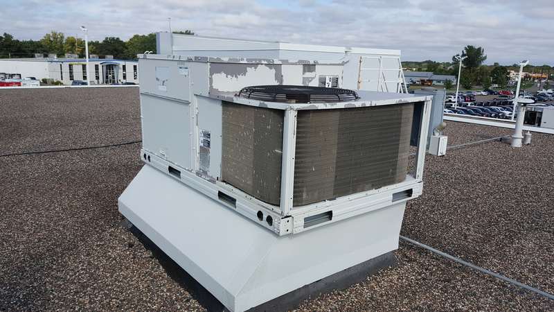 A rooftop HVAC unit on the old gravel roof at the Forest Lake dealership before the job