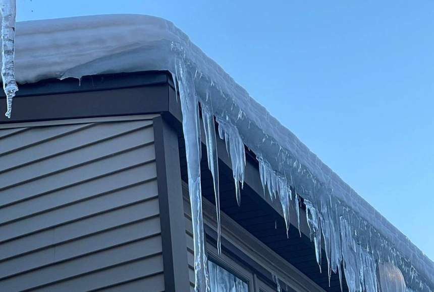 Ice dam and long icicles along the eave of a Wildwood Townhomes building in Apple Valley, February 2023