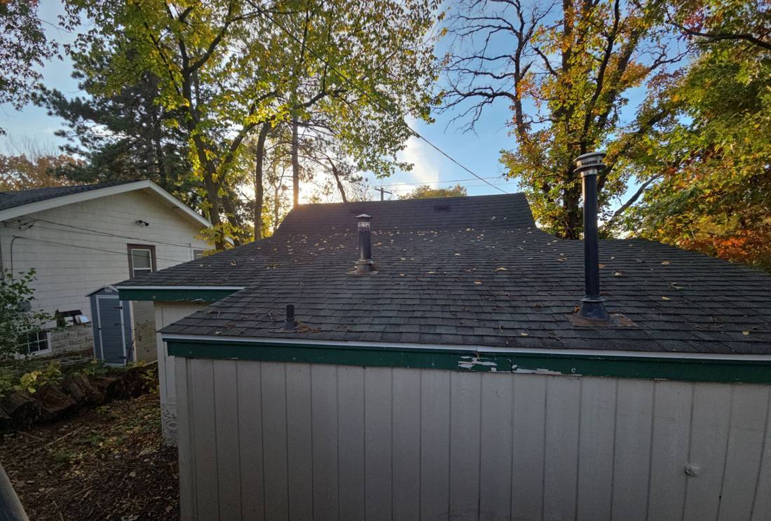 Detached garage with a dark shingle roof and green trim under fall trees in Mahtomedi, MN, photographed by Repair King in October 2025