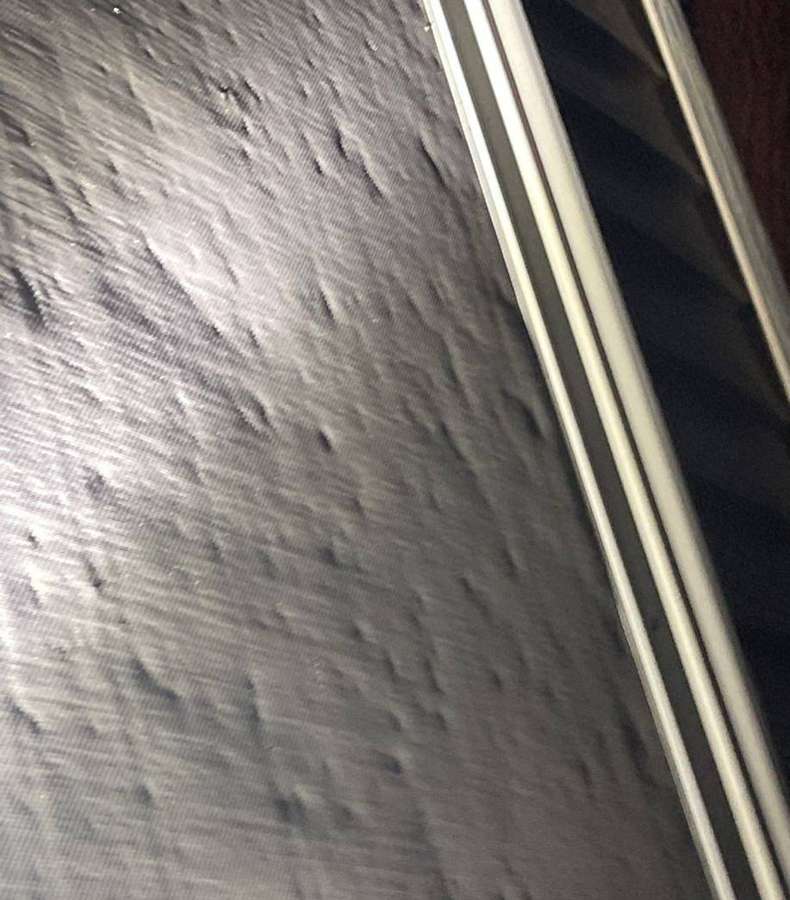 Hail dents in siding on a Buffalo home, photographed by flashlight in October 2021