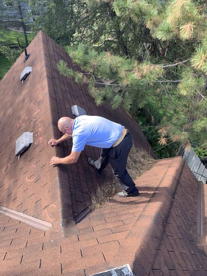 Repair King inspector checking shingles on the steep main roof of a Watertown home
