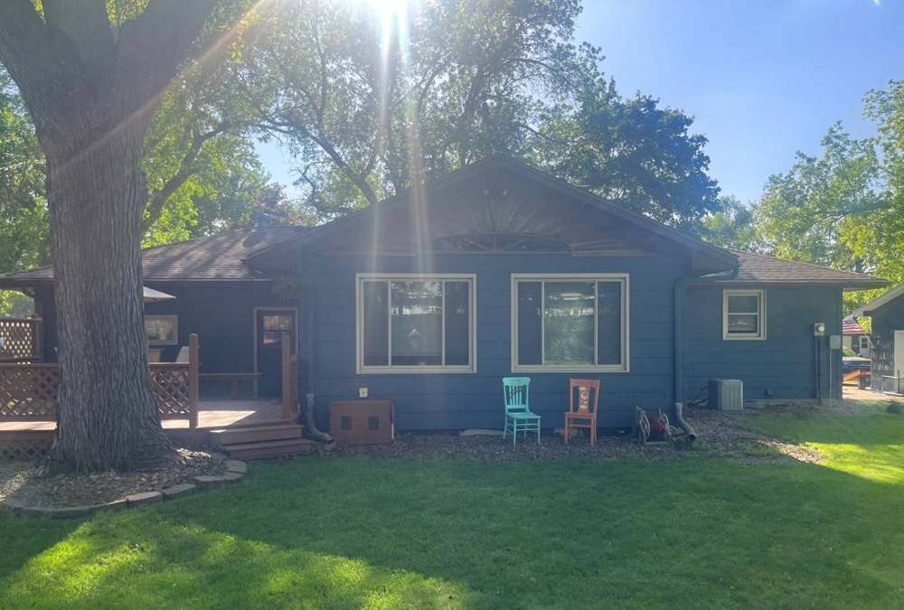Blue single-story home with a deck and large shade tree in Hutchinson, MN, photographed during a Repair King inspection in June 2024