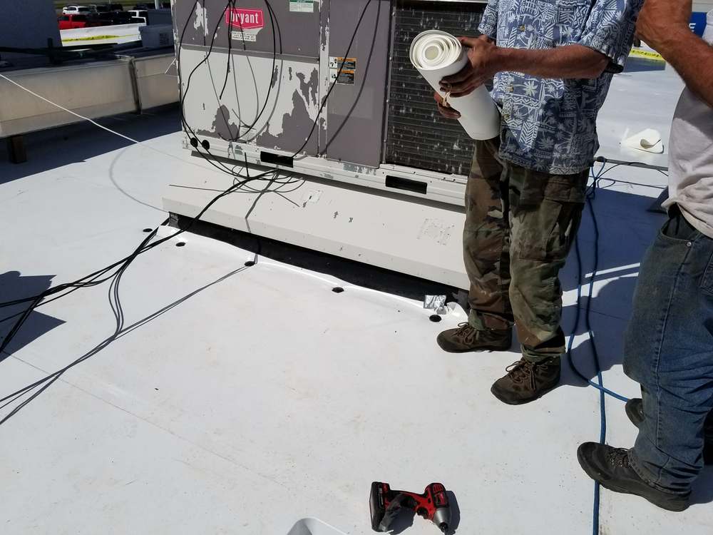 Repair King crew fitting white PVC flashing at the base of a rooftop HVAC unit on the Forest Lake Chrysler Jeep Dodge roof in Forest Lake, MN