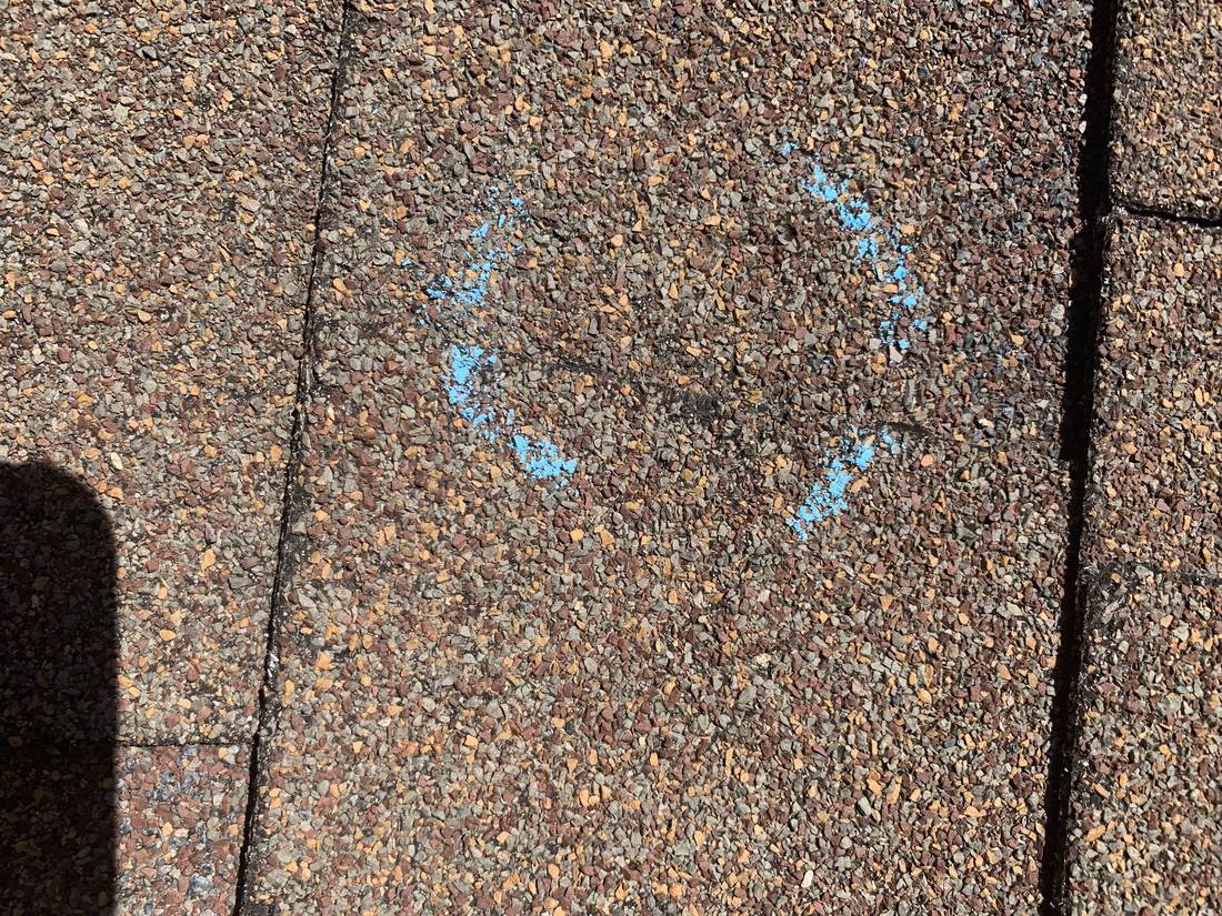 Blue chalk circle around a hail hit on a brown shingle at Heritage Estates in Dodge Center, MN