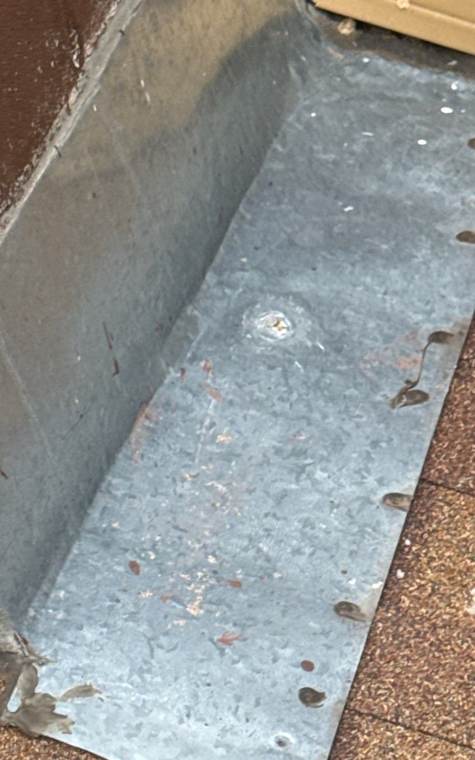 Dented metal flashing at a roof-to-wall joint on a Stacy home, June 2026