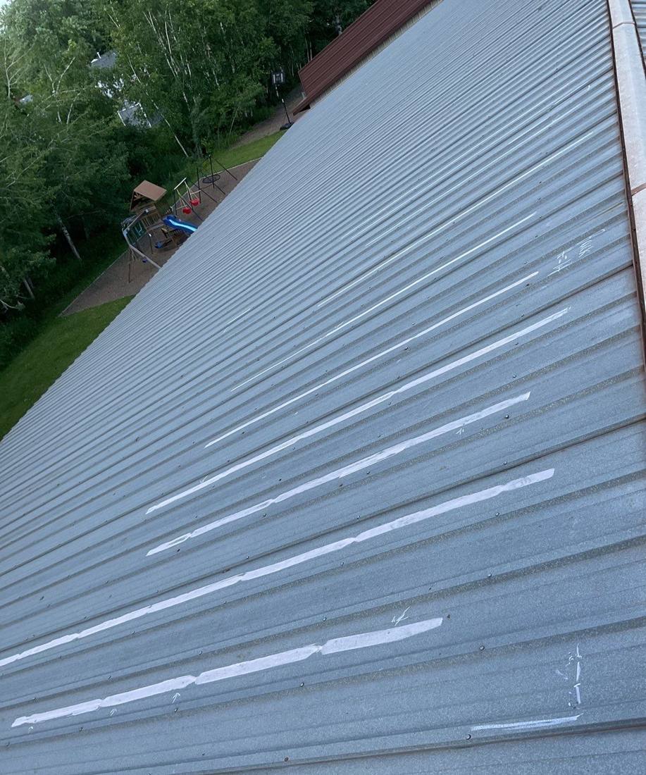 Chalk-marked hail streaks on a standing-seam metal roof in Sandstone, June 2024