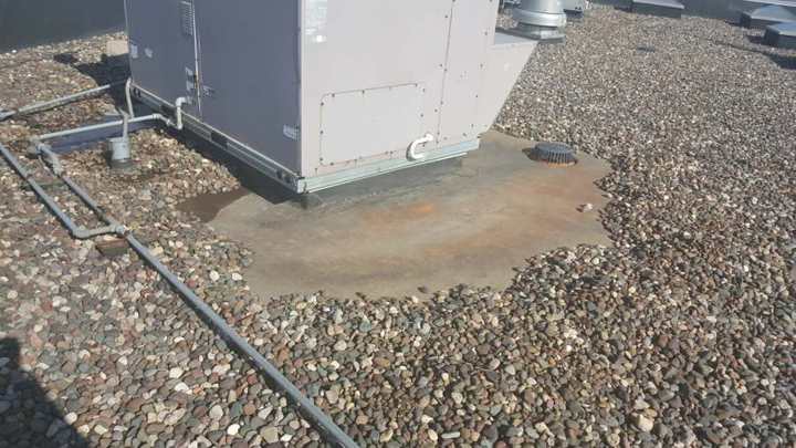 Rust-colored ponding stain spreading from a rooftop unit curb across the ballast on the Bobby & Steve's Auto World roof in downtown Minneapolis
