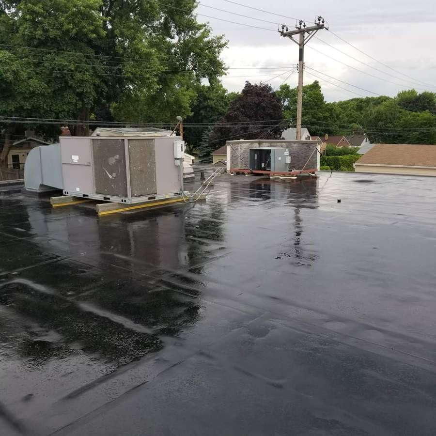 Ponding water around rooftop HVAC units on a West St. Paul strip-center roof after rain
