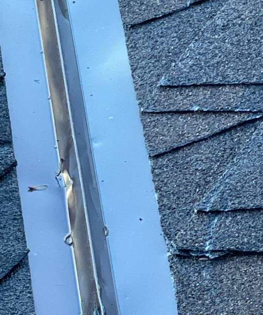 Hail-dented metal valley flashing beside asphalt shingles on the Radiance Medspa roof in Woodbury, September 2022
