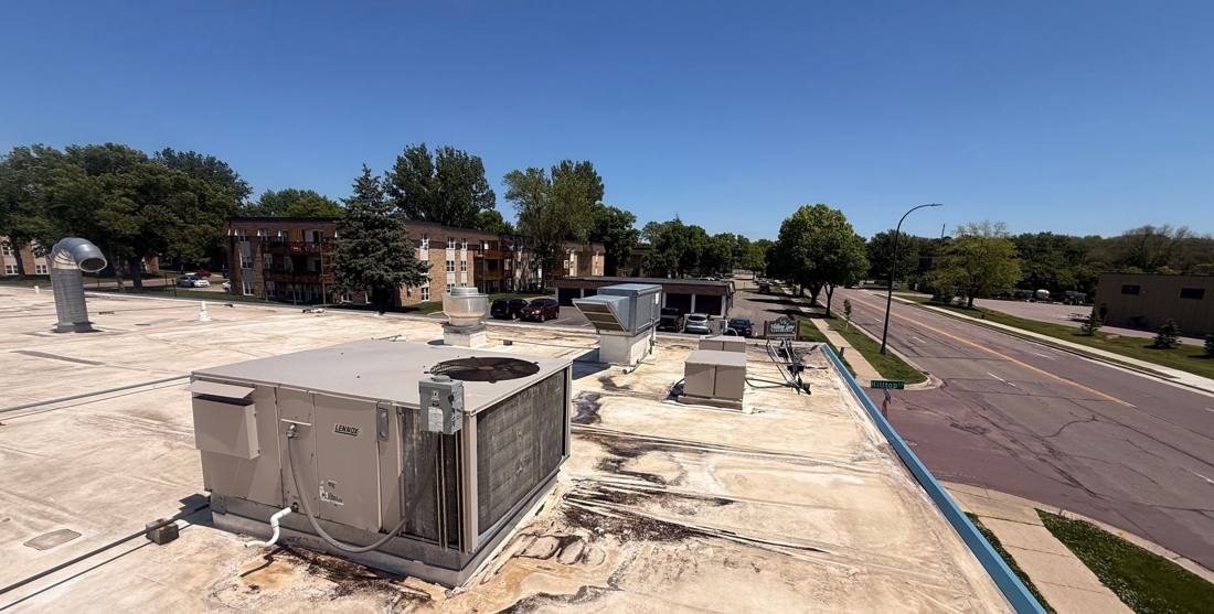 Rooftop HVAC unit on the Village East Center roof in Mankato, overlooking Hoffman Road, May 2026