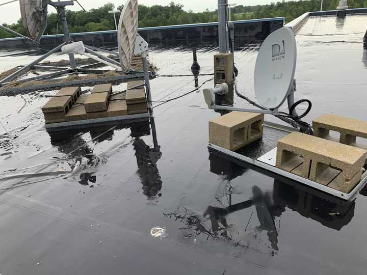 Satellite dishes on sleepers in standing water on the Pine City dealership roof, July 2019