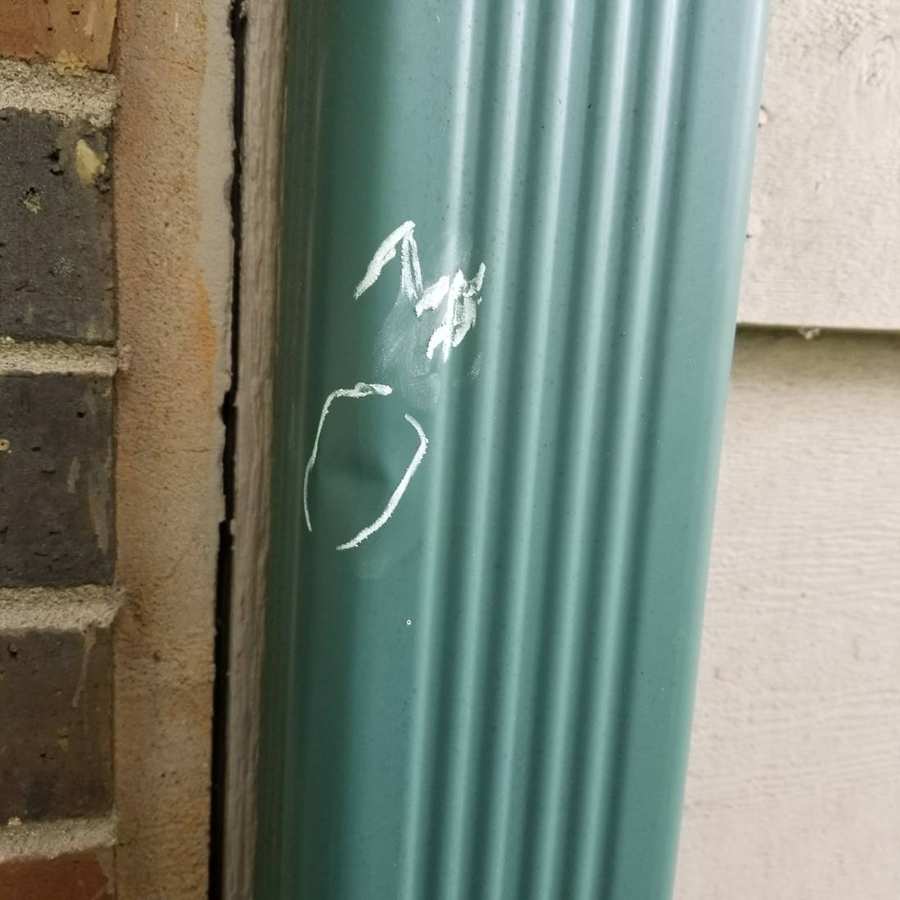 Chalk-marked dent in a green downspout on a Coon Rapids home, June 2017