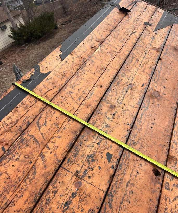 Original spaced board roof decking measured with a tape during a Repair King tear-off on a Richfield, MN home, April 2025