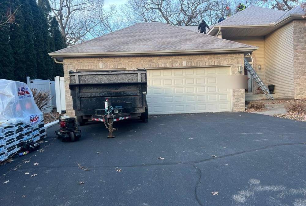 Tear-off day at a Fridley home: dumpster trailer staged and crew starting on the roof, December 2023