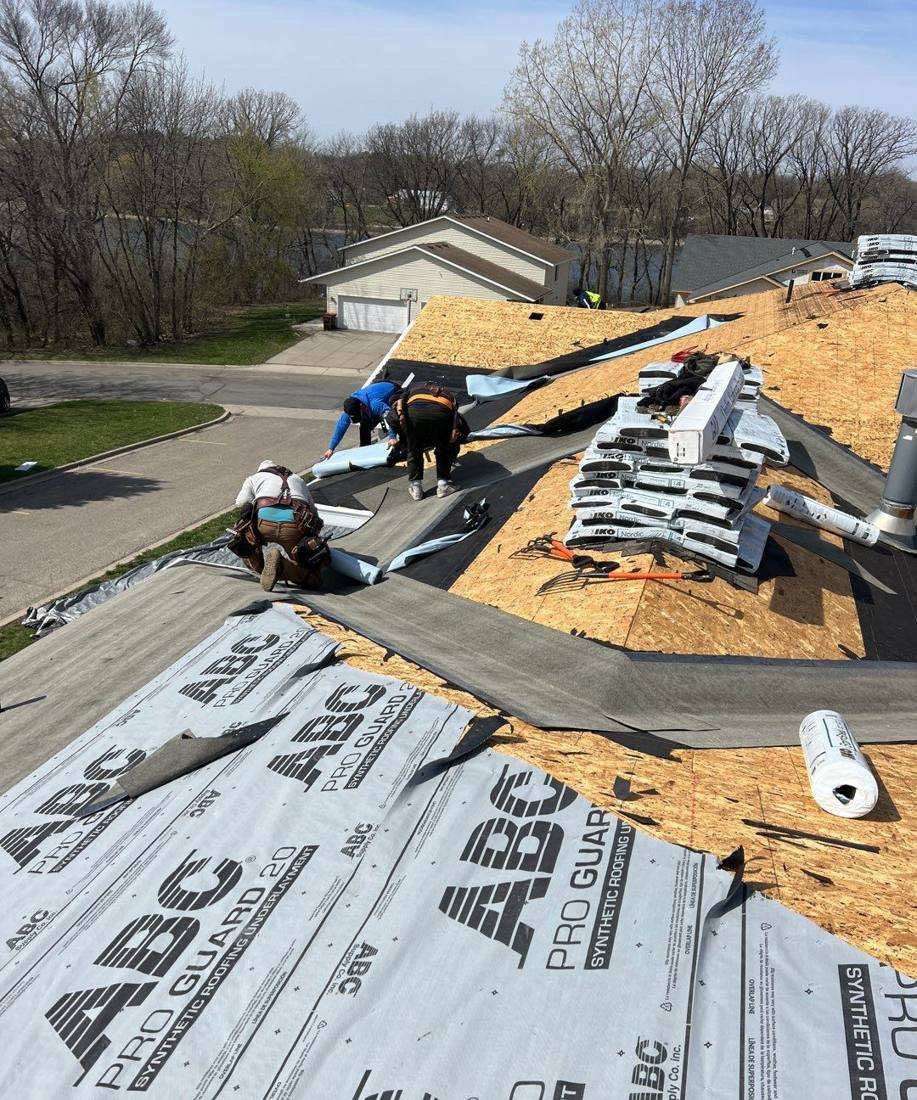 Repair King crew installing synthetic underlayment and staging shingle bundles during the Waters Edge townhome re-roof in Howard Lake, April 2024