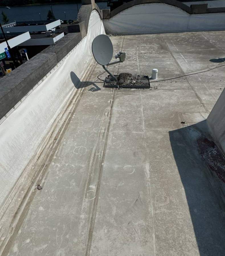 The membrane roof at 106 South Main Street, with the parapet wall and a satellite dish mount, September 2024