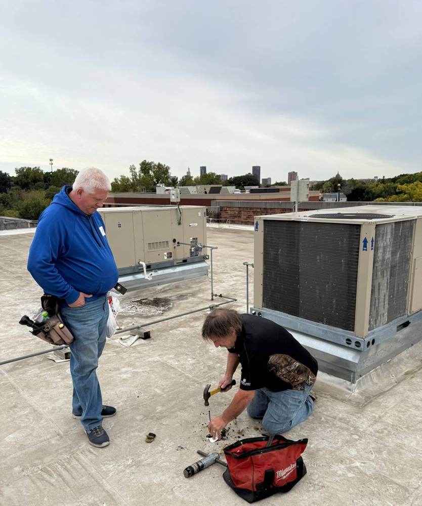 Repair King team member working beside a rooftop unit on the flat roof of HOPE Community Academy in St. Paul, MN, October 2024