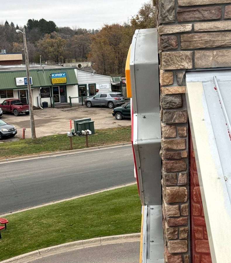 Coping and stone veneer at the roof edge of the Delano Dairy Queen, with Highway 12 businesses in the background, November 2023