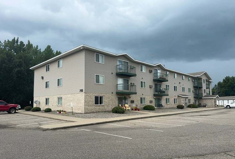 Ridgedale Square Apartments, a three-story tan apartment building with balconies on Ridge Ave NE in Hutchinson, MN, July 2024