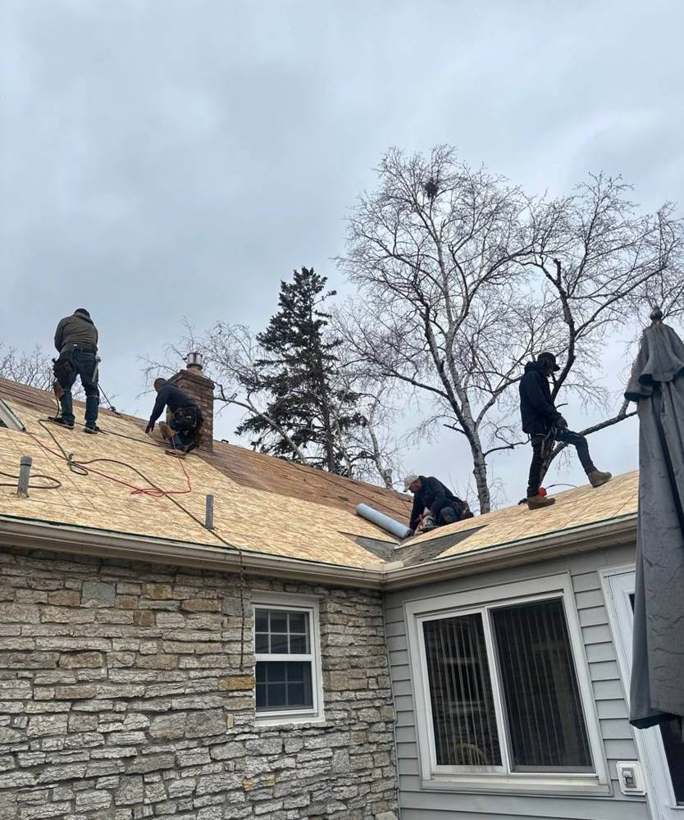 Repair King crew on the roof of a stone-faced Richfield, MN home laying new sheathing during an April 2025 re-roof