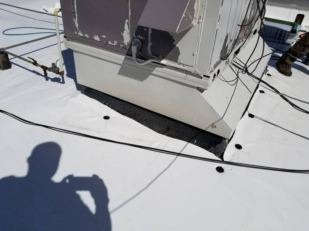A rooftop unit curb wrapped in new white PVC flashing on the Forest Lake dealership roof