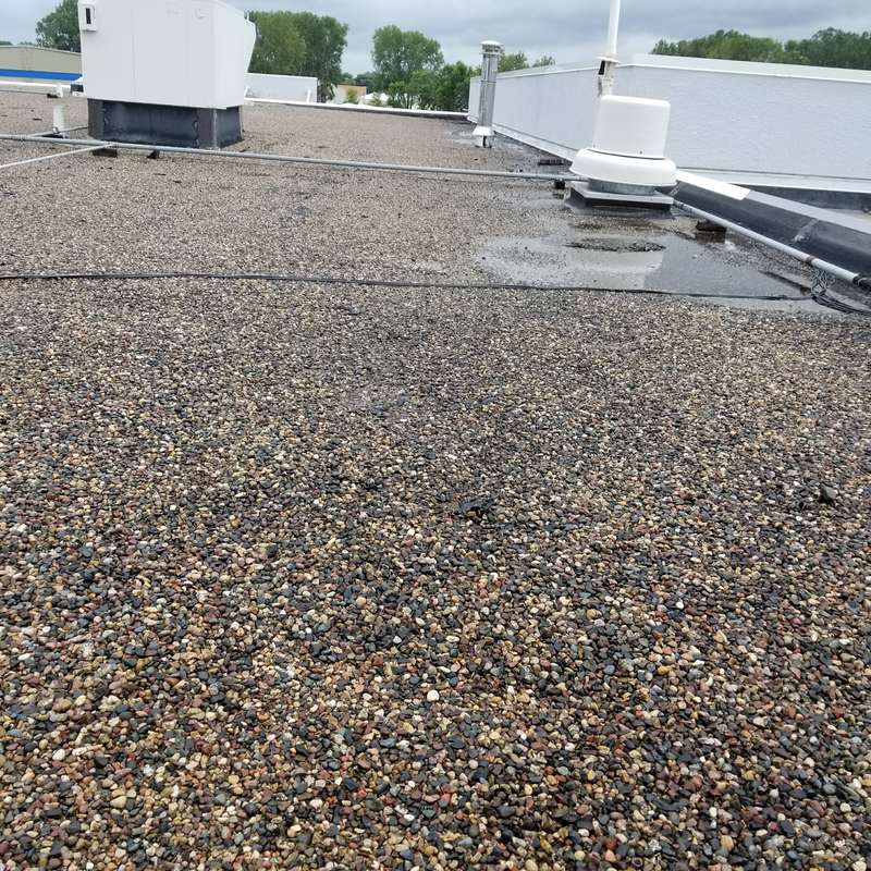 The weathered gravel roof and rooftop vents at Forest Lake Chrysler Jeep Dodge before the job