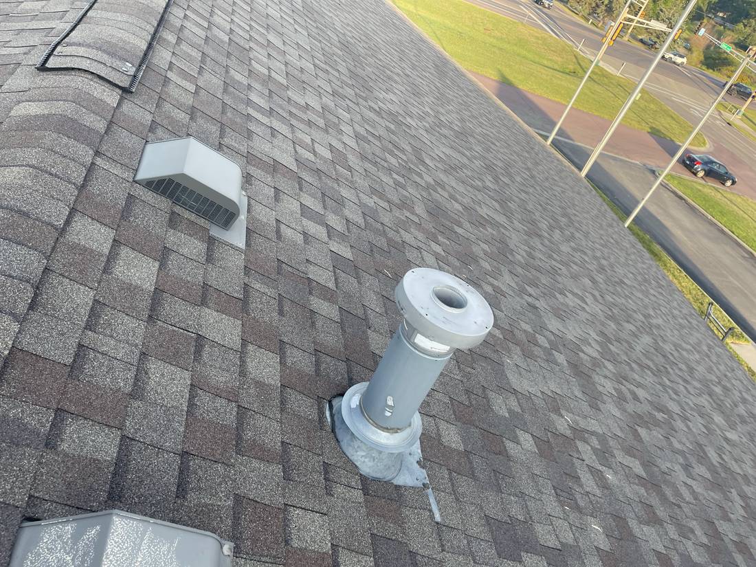Box vent and plumbing vent stack on the GrandStay Hotel roof in Waseca, MN, with State Street North below